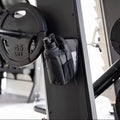 Black weight plate attached to a barbell with a small black bag on a gym bench.