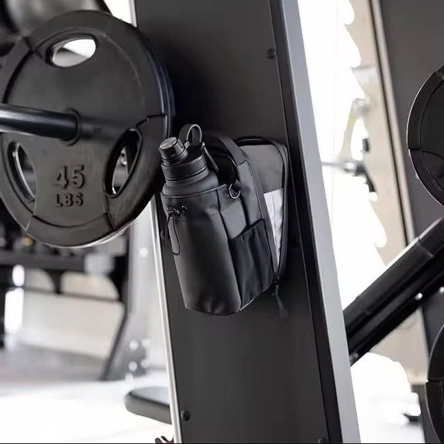 Black weight plate attached to a barbell with a small black bag on a gym bench.